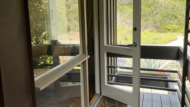 Een houten terras met een glazen deur naar een patio.