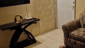 A room with a black table, a ring, a router, and a patterned armchair. - 2-Bed, Sleeps 4, Private Garden, Parking (Portmore)