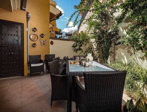 Eine Terrasse mit Korbmöbeln, einem Glastisch und Dekorationselementen.