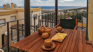 A balcony with a wooden table set for tea, a teapot, cups, and a pastry. - Manilva Coastal Retreat for over 50 's (Manilva)
