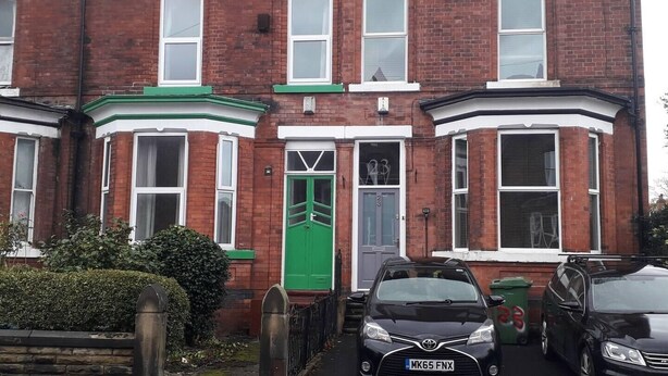 A red brick terraced house with a green front door, white-framed windows, and a garage. - Grand 4-Bed Quasi semi House in Manchester (Manchester)