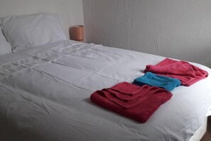 A bed with white sheets and two towels, one red and one blue, placed on it. - Grand 4-Bed Quasi semi House in Manchester (Manchester)