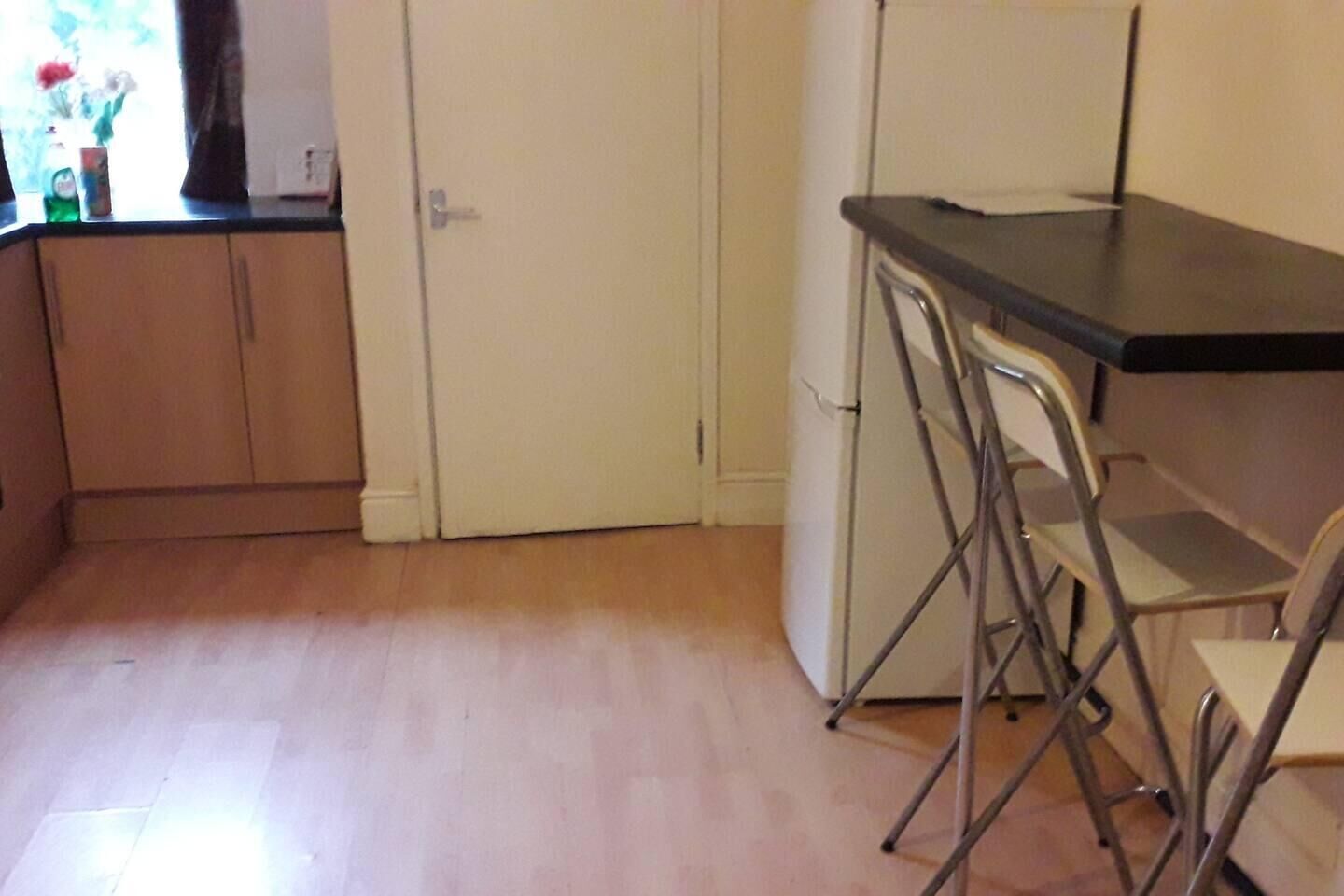 A kitchen with wooden cabinets, a white door, and a bar area with metal stools.