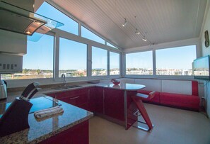 Una cocina moderna con ventanas amplias, un banco rojo y vistas a la ciudad.