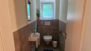 A narrow bathroom with a sink, toilet, and a small window. - Apartment "Petra" with Mountain View, Balcony & Wi-Fi (Kössen)