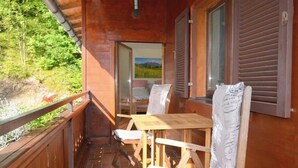 A wooden cabin with a balcony, a table, and chairs. - Apartment "Petra" with Mountain View, Balcony & Wi-Fi (Kössen)