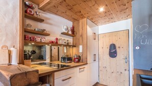 A kitchen with wooden shelves, a sink, and a door with a heart decoration. - Chalet "Alpine Time-Out in Swiss Pine Wood" with Mountain View in Inzell near Ruhpolding (Inzell)