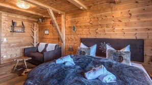 A wooden cabin interior with a bed, a sofa, a small table, and a ladder. - Chalet "Alpine Time-Out in Swiss Pine Wood" with Mountain View in Inzell near Ruhpolding (Inzell)