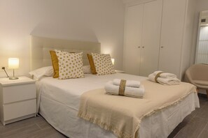 A neatly made bed with pillows, a bedside lamp, and a folded towel on a bedside table. - RENTHAS Fernando Lessesps I (Malaga)