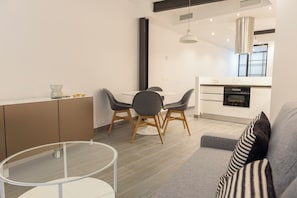A modern kitchen with a built-in oven and a dining area with a round table and chairs.