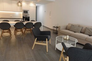 A modern living room with a sofa, a glass coffee table, and a dining area with chairs and a table. - RENTHAS Fernando Lessesps I (Malaga)