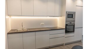 Eine moderne Küche mit Spüle aus Edelstahl, einer eingebauten Mikrowelle und einem Backofen.