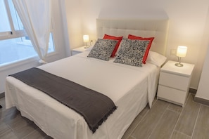 Ein Hotelzimmer mit einem Bett, zwei Nachttischen, einem Fenster mit Vorhängen und einer Nachttischlampe.