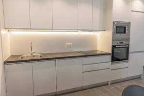 Una cocina moderna con un lavamanos de acero inoxidable, un microondas integrado y un horno.