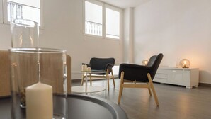 Ein modernes Wohnzimmer mit einem Glastisch, zwei Stühlen, einem weißen Schrank und einem großen Fenster.
