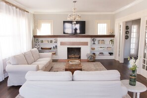 Una sala de estar con chimenea, un televisor montado encima y un candelabro.