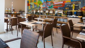 A restaurant with a colorful mural, wicker chairs, and a buffet area. - Cordela Inn Bengkulu (Bengkulu)
