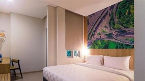 A hotel room with a large bed, a desk with a chair, and a wall-mounted TV. - Cordela Inn Bengkulu (Bengkulu)