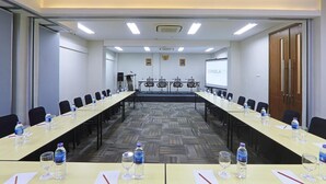 A conference room with long tables, chairs, water bottles, glasses, and a projector screen displaying "CORDELAINN". - Cordela Inn Bengkulu (Bengkulu)