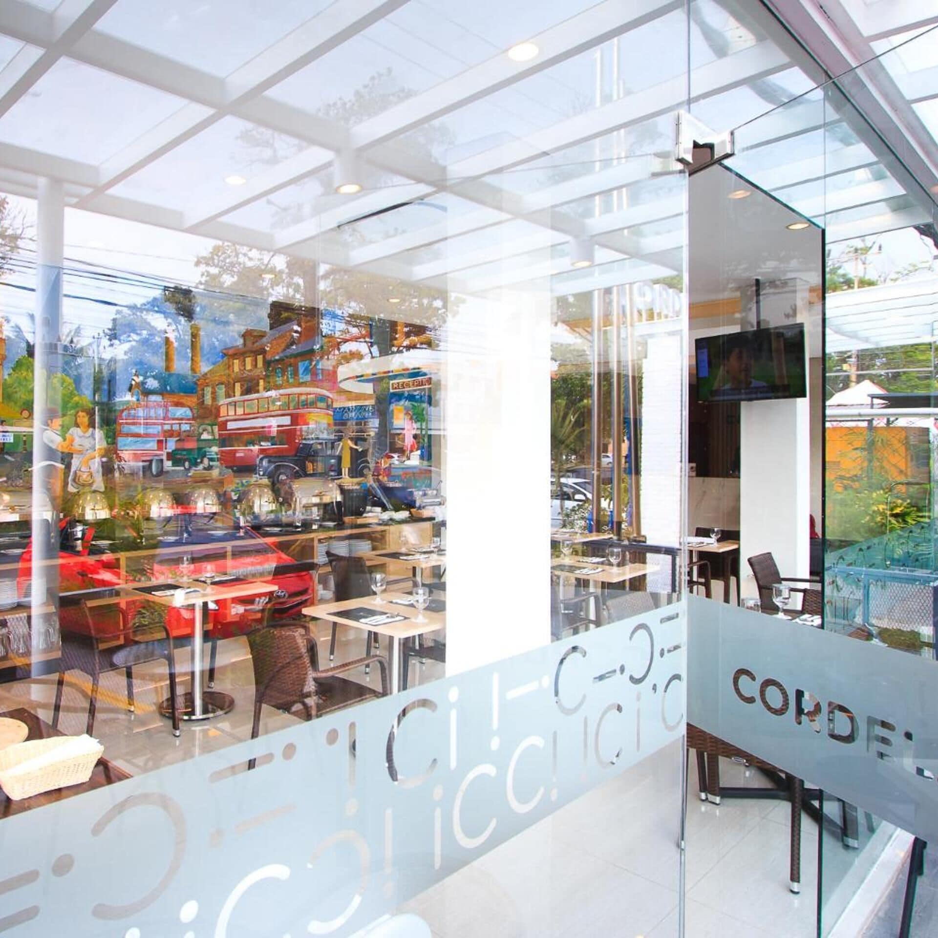 A modern interior with a glass wall, a reception area, and a seating area with tables and chairs.