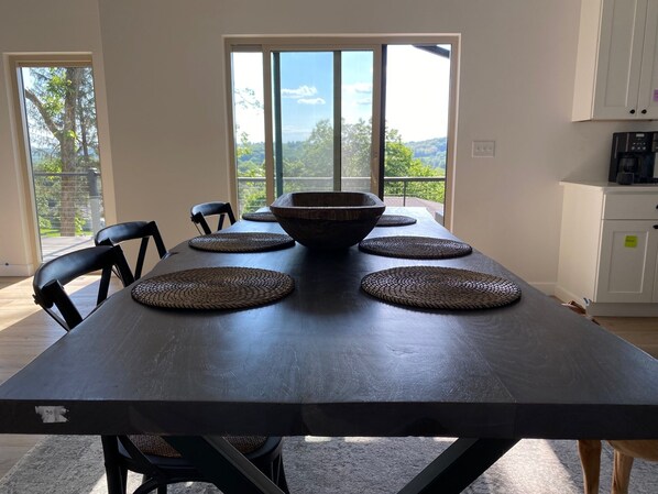 Een eettafel met een donker tafelblad, vier geweven plaatszetters en een grote schaal in het midden.