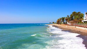 A beach with clear blue water, a sandy shore, and a row of palm trees. - Calahonda Royale Seaview Suite, Mijas Costa, Spain (Mijas Costa)