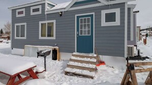 Kaksikerroksinen talo, jossa on sininen etuovi, valkoiset ikkunat ja katettu kuisti.