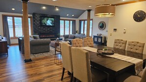 A spacious living room with a fireplace, comfortable seating, and a dining area with a large table.