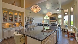 A spacious kitchen with a large island, pendant lighting, and a view to the living area. - Luxe Scottsdale Home w/ Pool & Mountain Views! (Scottsdale)