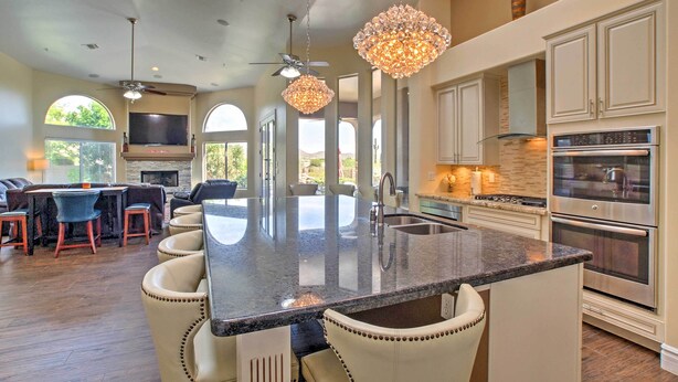 A spacious kitchen with a large island, modern appliances, and a dining area with leather chairs. - Luxe Scottsdale Home w/ Pool & Mountain Views! (Scottsdale)
