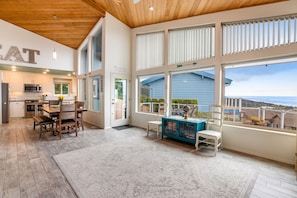 Enjoy expansive views from the large windows in this room, featuring a modern kitchen, dining area, and cozy seating space.
