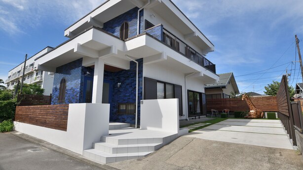 Une maison moderne à deux étages, dotée d’un balcon, d’un garage et d’une pelouse bien entretenue.
