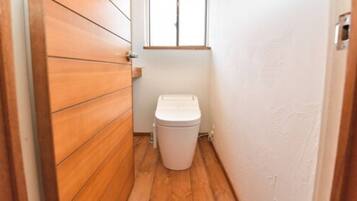 A narrow hallway with wooden flooring and a white toilet.