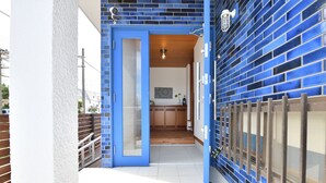 Un couloir avec une porte bleue qui donne sur une cuisine.