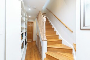 Una escalera de madera con barandilla blanca que lleva a una puerta en la parte superior.