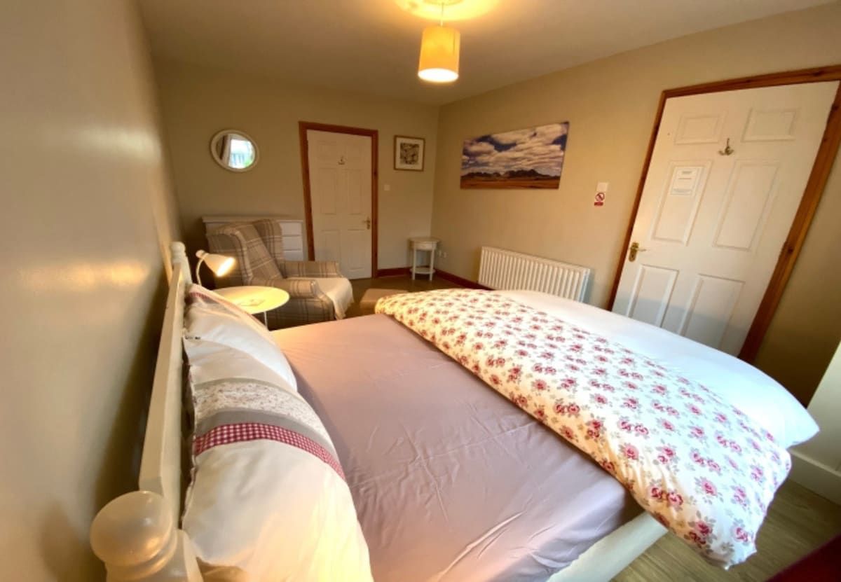 A bedroom with a bed, bedside tables, a radiator, and a door.