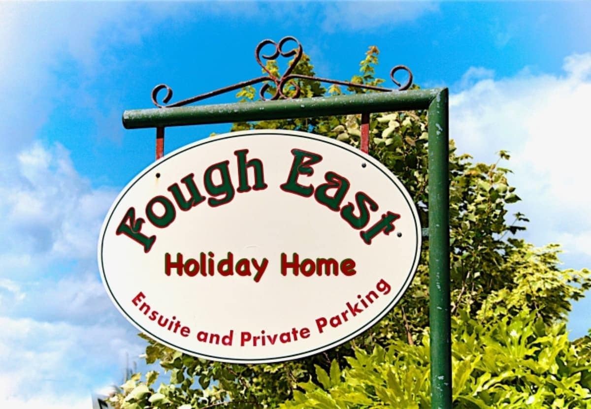 Une enseigne indiquant « Fough East Holiday Home » avec la mention « Salle de bain privative et parking privé ».