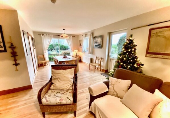 A cozy living room with a sofa, a dining table, and a Christmas tree.