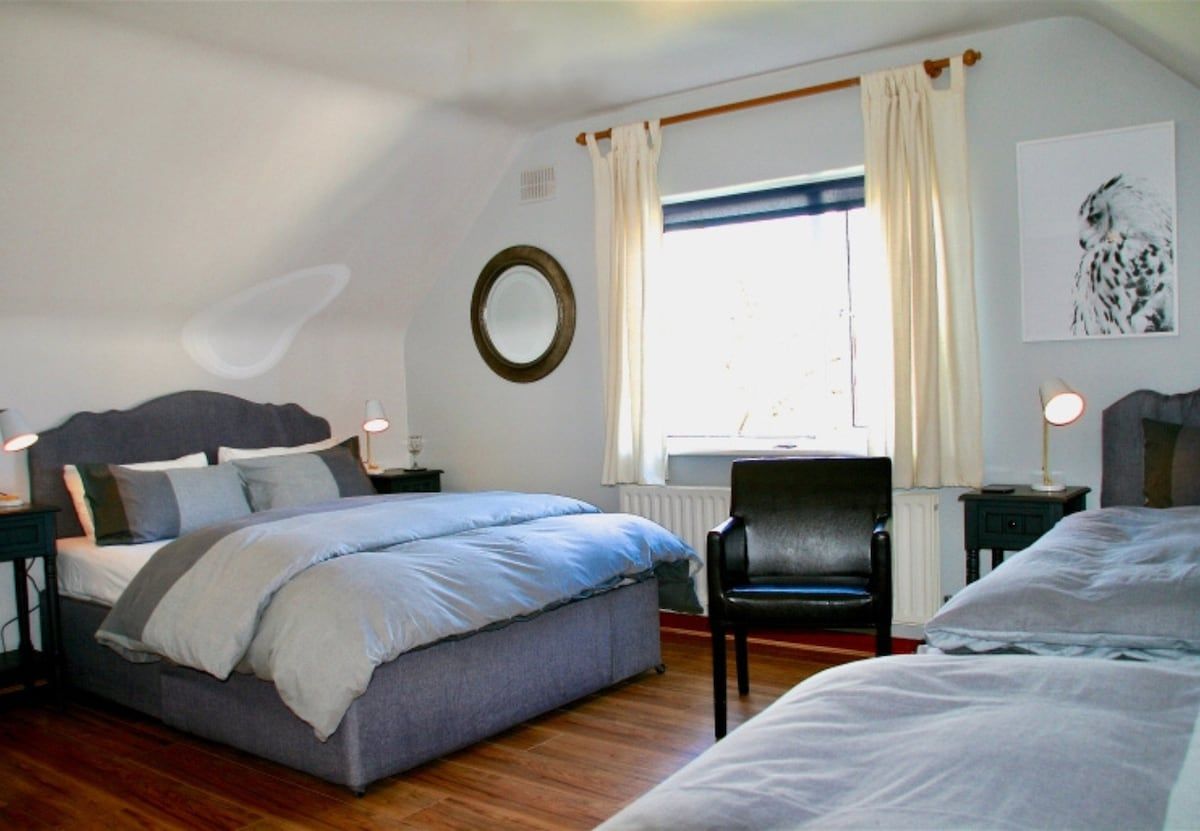 Une chambre à coucher avec un lit, une chaise, un bureau et une fenêtre avec des rideaux.