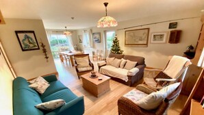 A cozy living room with a blue sofa, a beige sofa, and a wicker chair. There is a wooden coffee table and a Christmas tree in the background. - Fough East, Cozy and close to town (Oughterard)