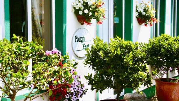 A building with green shutters, flower baskets on the wall, and a sign that reads "Kough East". - Fough East, Cozy and close to town (Oughterard)