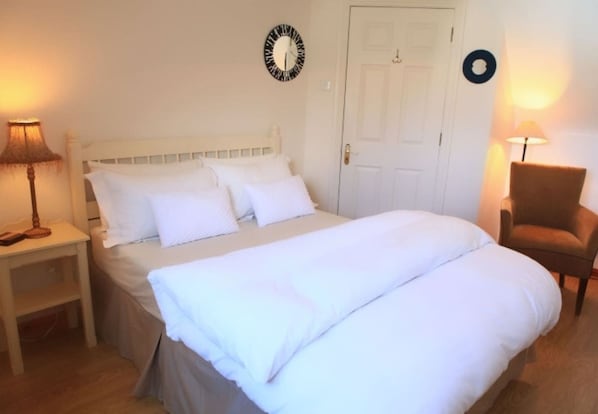 A bedroom with a bed, two bedside tables, a chair, and a door.