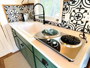 A kitchen with a stove, sink, and decorative backsplash.