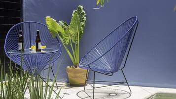 A blue chair and a table with bottles and a lemon on a patio next to a pool.