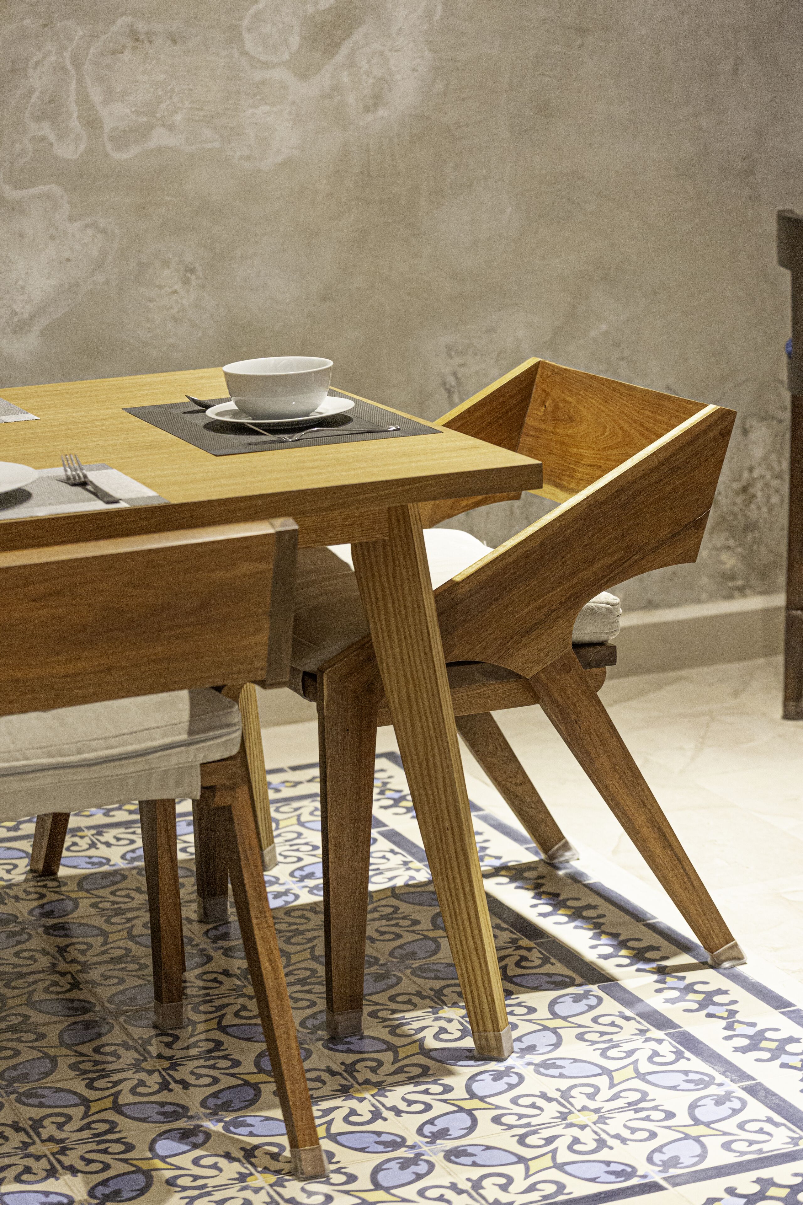 A wooden dining table with a bowl and napkin set on a mat.