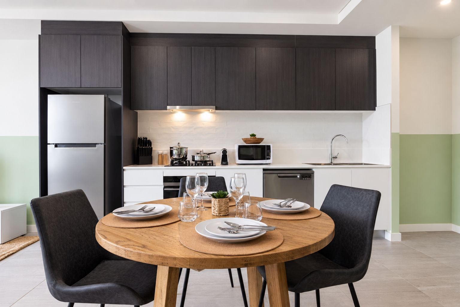 A modern kitchen with dark cabinets, a stainless steel refrigerator, a microwave, and a dishwasher.