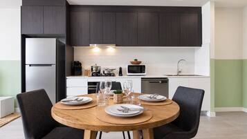 A modern kitchen with dark cabinets, a stainless steel refrigerator, a microwave, and a dishwasher.
