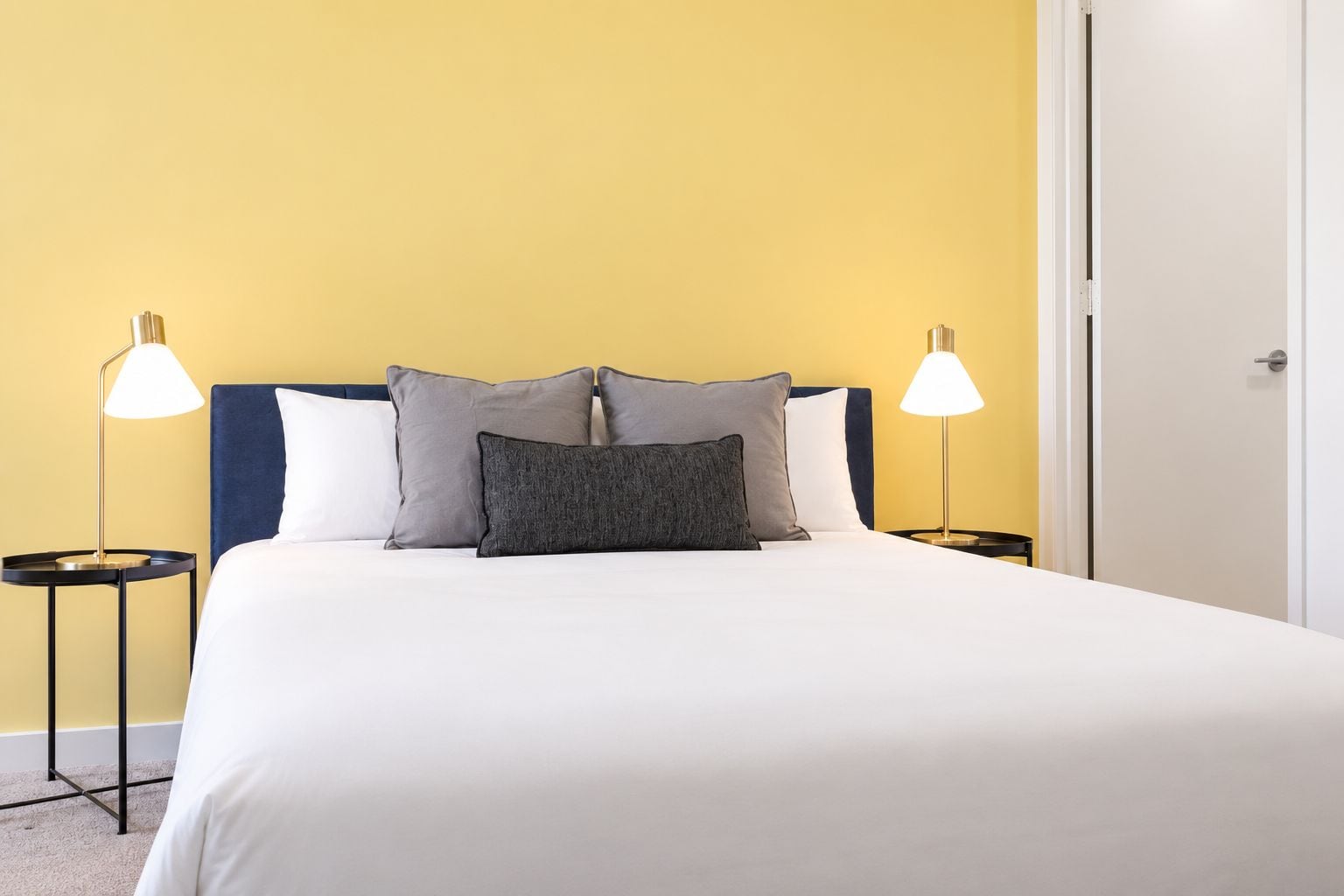 Una habitación de hotel con una cama, dos mesitas de noche y dos lámparas.