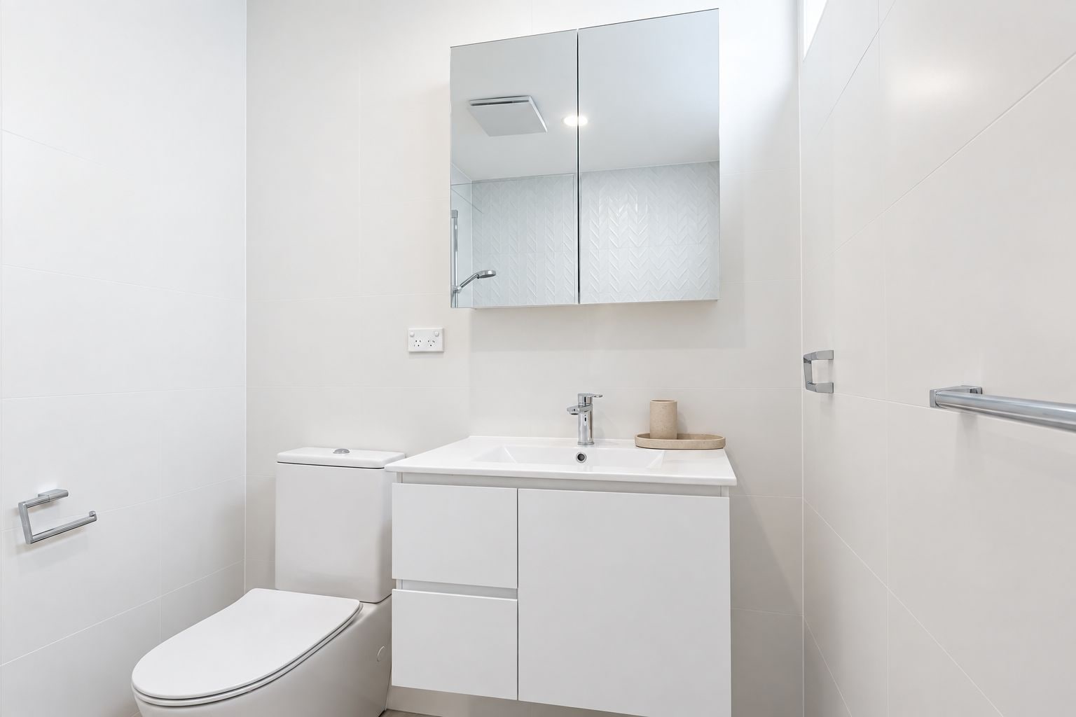 Un baño moderno con inodoro, lavabo y espejo.