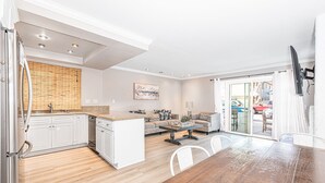 A modern kitchen with white cabinetry, a wooden countertop, and a dining area with a wooden table and chairs.